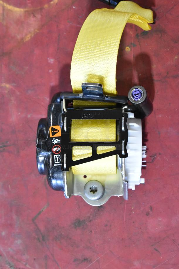Yellow seat belt retractor mechanism on red surface, visible safety symbols, and serial number 240513.
