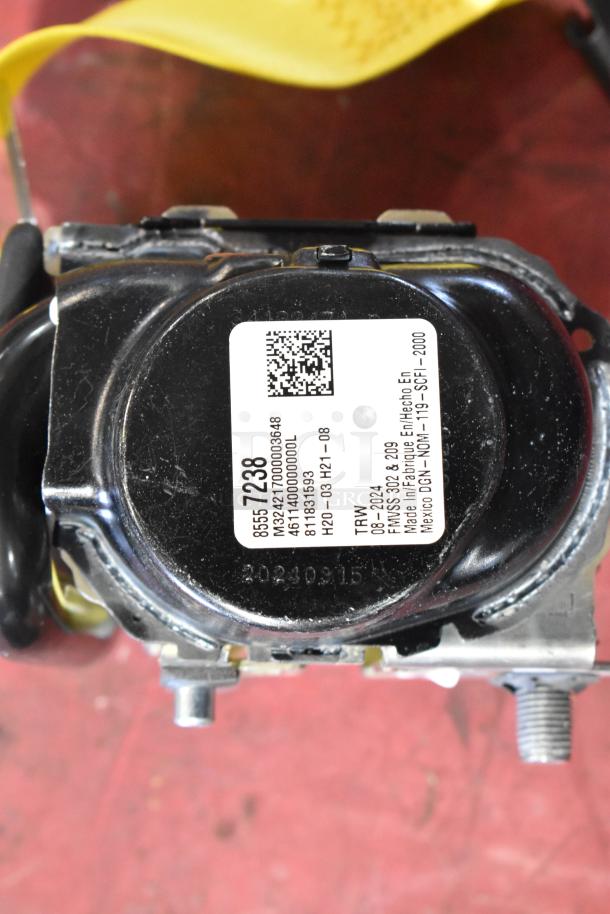 Seat belt retractor with a visible label showing product and manufacturing details. In good condition.