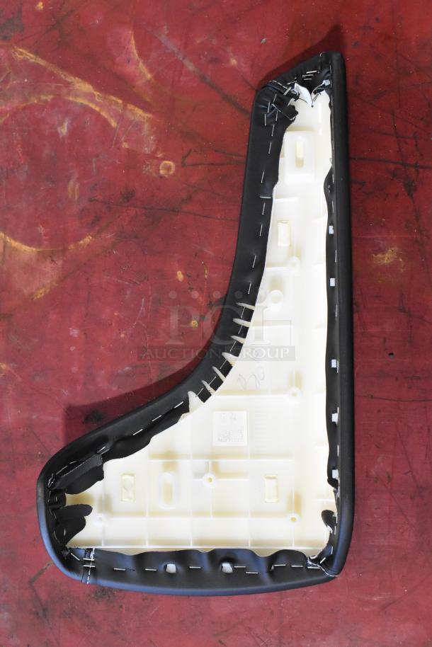Alt text: Plastic interior panel with black trim, possibly for a Camaro. Visible staples, some fabric wear, on red background.