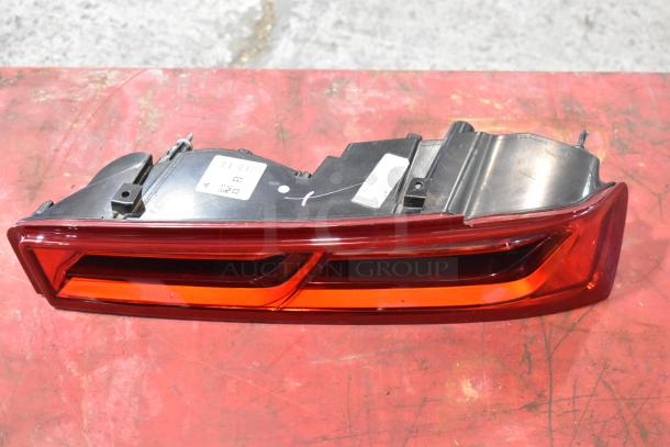 Red automotive brake light with black housing, visible labels, good condition, part of a three-item auction lot.