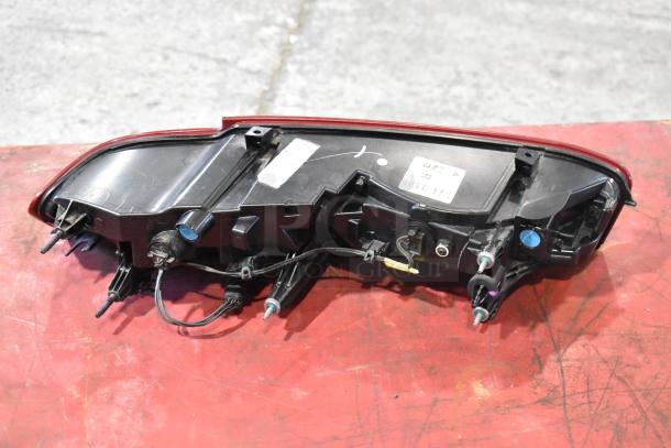 Brake light assembly on red surface; contains wiring and connectors. Good condition with visible manufacturer's label.