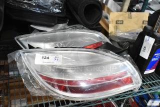 Two new brake lights, in clear plastic wrap, with a label marked "124, QTY X2," on a shelf.