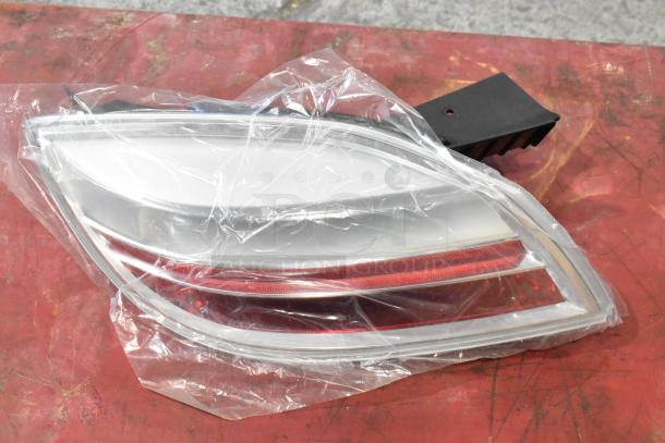 Clear brake light in packaging on red surface, mint condition, aerodynamic design; auction includes two units.