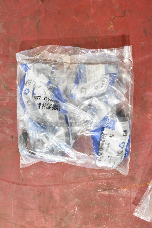 Bag of automotive items, including ACDelco gear oil bottles and miscellaneous parts. Labels show GM and product numbers.