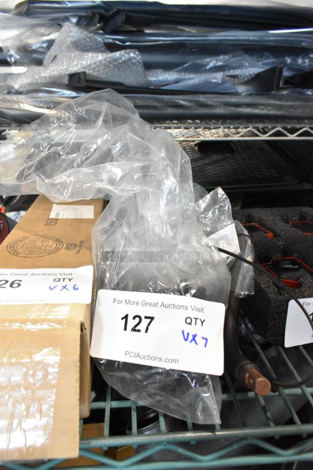 7 various items including GM 22751230 door latch release switch, GM 20959449 rear suspension stabilizer shaft clamp, auction quantity tags.