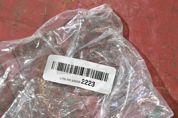 Clear plastic bag containing GM parts, labeled "LPN RR 83558 2223," including door latch and stabilizer clamp.