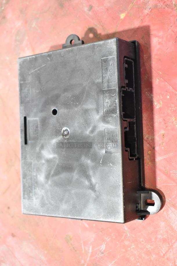 Black rectangular plastic auto part with connectors visible on the side, labeled "GRAY GPS" and "BATT ICH."