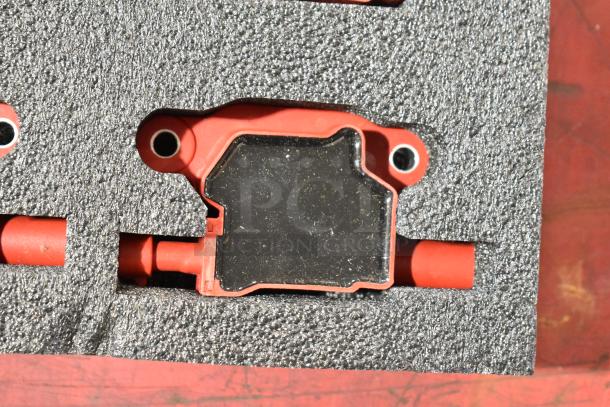 Close-up of a red and black mechanical component in foam packaging. Appears in good condition.