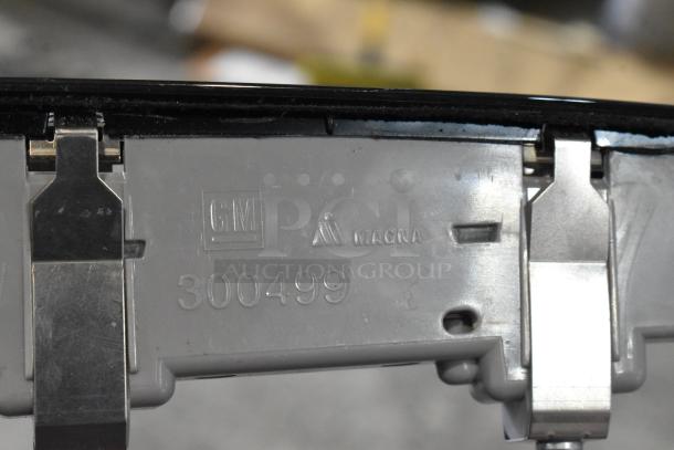 Close-up of a GM 300499 component, featuring GM and MAGNA logos, showing metal and plastic construction details.