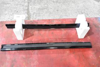 Two black spoilers with glossy finish, item number 23376474, in pristine condition, displayed with white stands on red surface.
