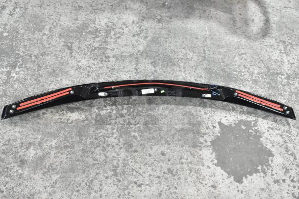 Black car spoiler model 23376474 with red accents and mounting holes, in excellent condition, displayed on concrete floor.