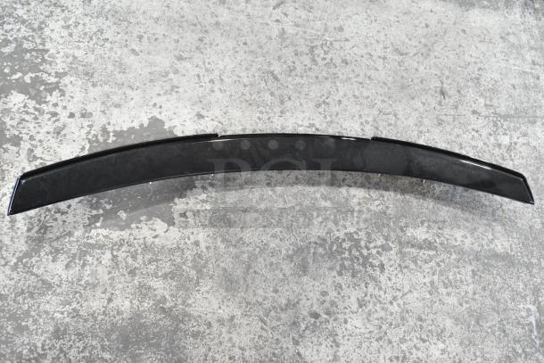 Black car spoiler, model 23376474, in good condition, with a sleek design, lying flat on a textured surface.