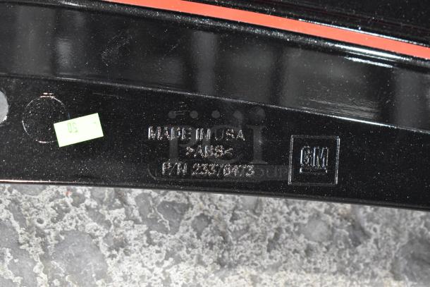 Black GM car spoiler, part number 23376473, made in USA, shown on a textured gray surface. Mint condition.
