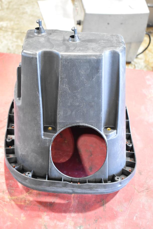 Black plastic automotive part with circular opening, lightly worn. Includes fasteners, suitable for assembly.