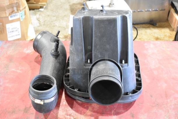 Box of parts including a black air filter housing and tube, used condition, with visible attachment points and seals.