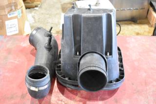 Box of parts including a black air filter housing and tube, used condition, with visible attachment points and seals.