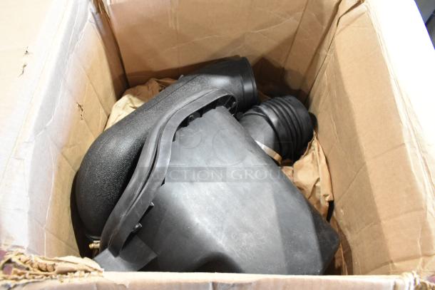Cardboard box containing automotive parts including a black air filter, hoses, and connectors, in good condition.