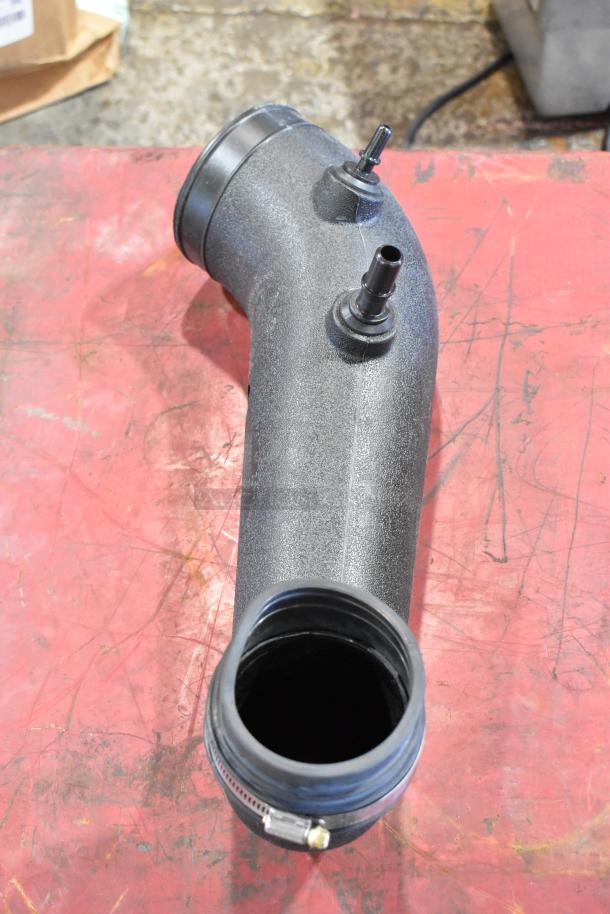 Plastic automotive pipe with two connectors, black textured finish, clamp at one end, for auction part box.