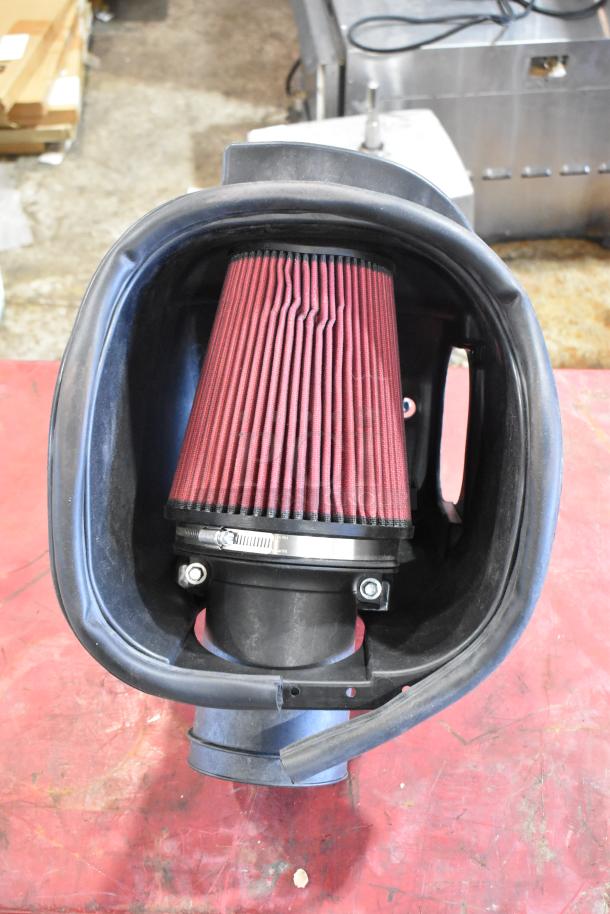 Box of parts with a red pleated filter, mounted in a black plastic housing. Appears in good condition, suitable for use.