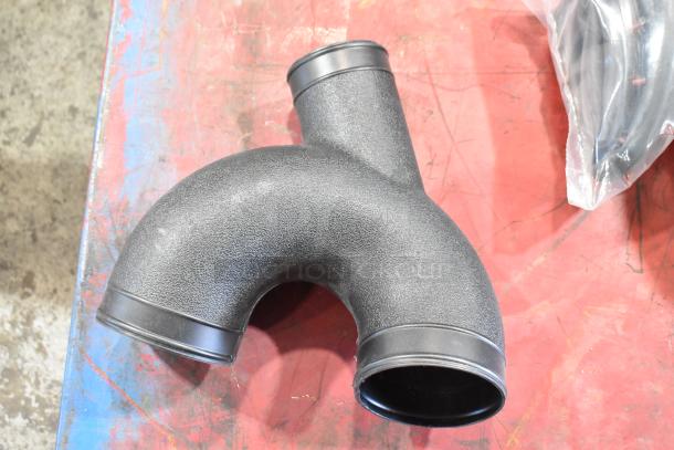 Box of automotive parts featuring a textured black plastic air intake manifold in good condition.