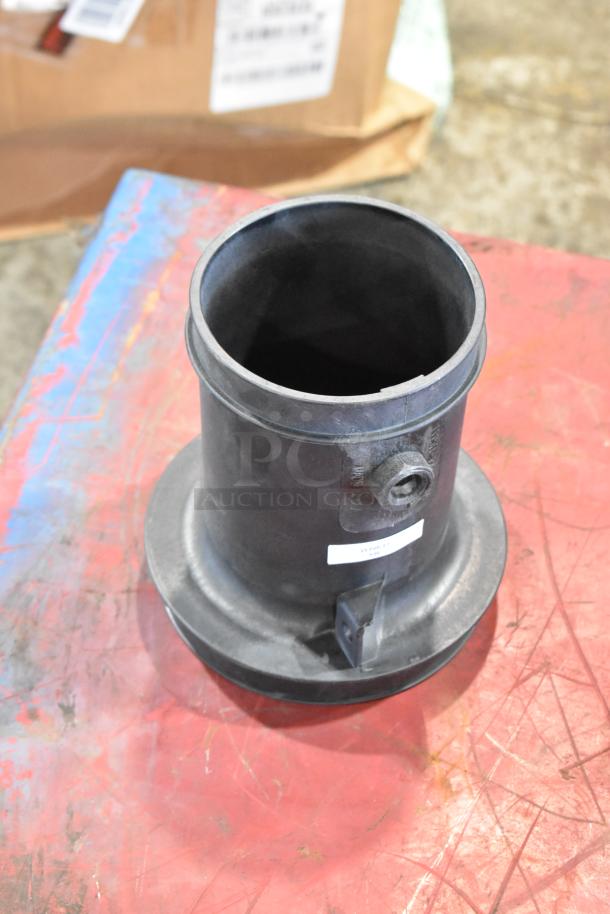 A large black plastic filter piece from a box of parts, labeled with a white sticker, on a red and blue surface.