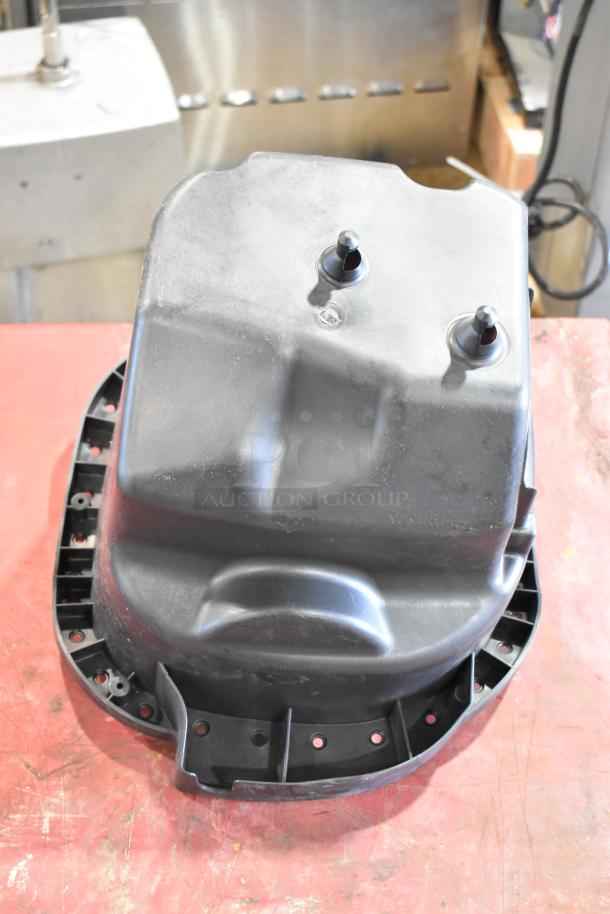 Black automotive filter housing with dual nozzles, shown on a workshop table. Appears in good condition.