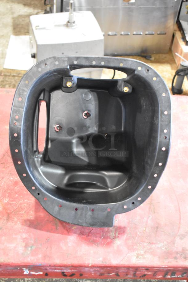 Box of parts including a black automotive filter housing, showing mounting holes and structural features. Condition appears unused.