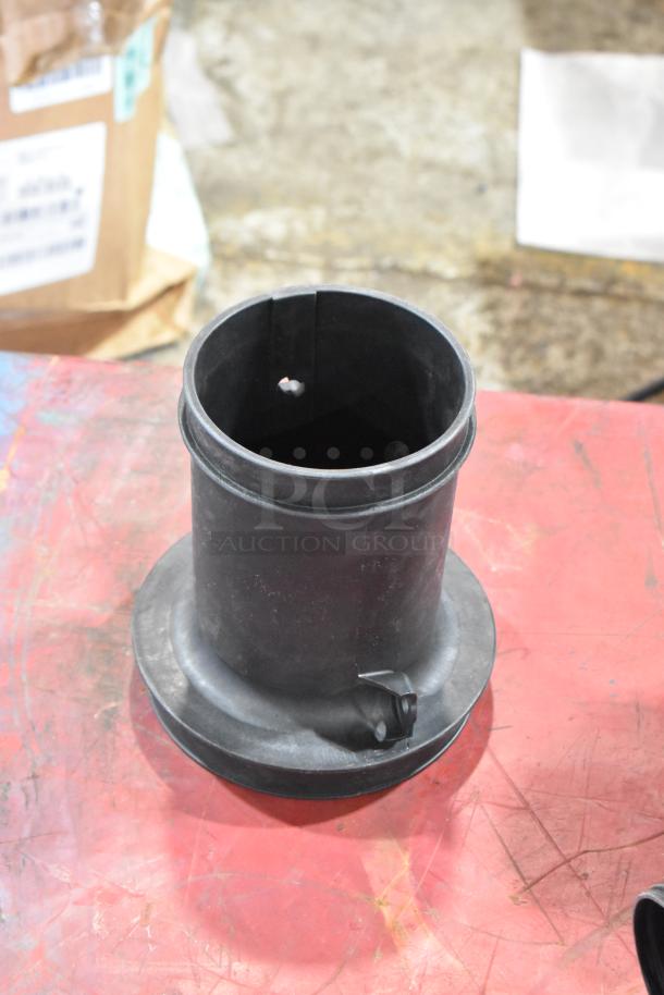 Box of mechanical parts featuring a black cylindrical filter, in used condition, on a red surface.