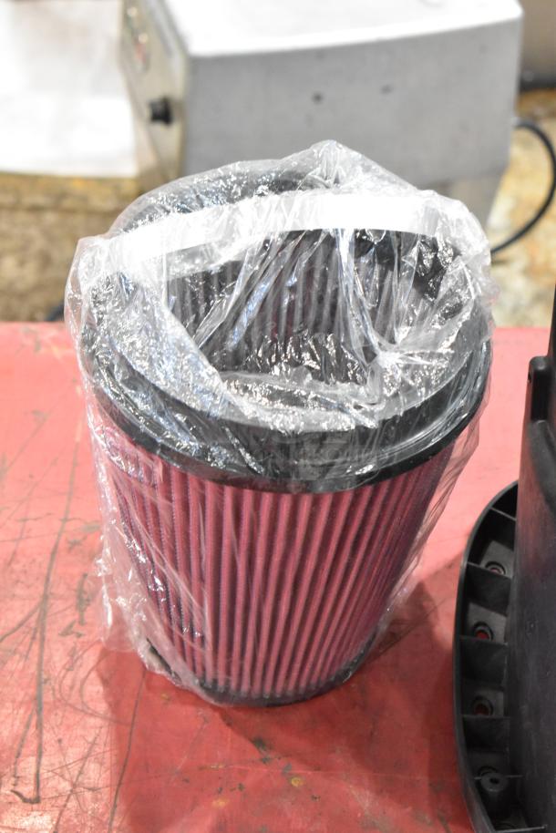 Plastic-wrapped air filter from a box of parts, on a red surface, in excellent condition.
