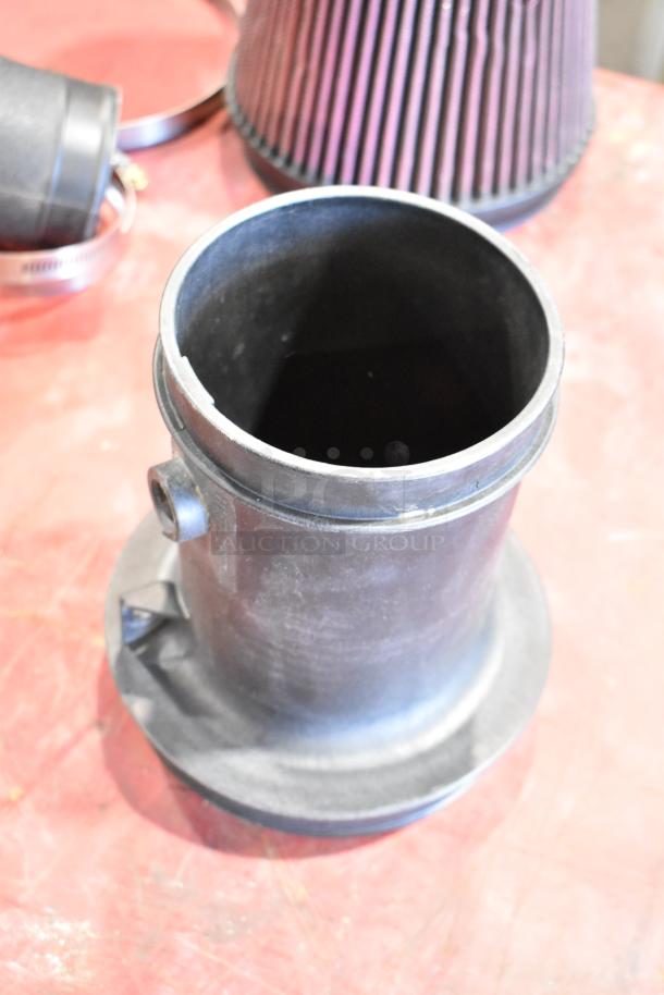 Box of parts featuring a cold air intake kit, including a filter, hoses, and clamps. Items appear in used condition.