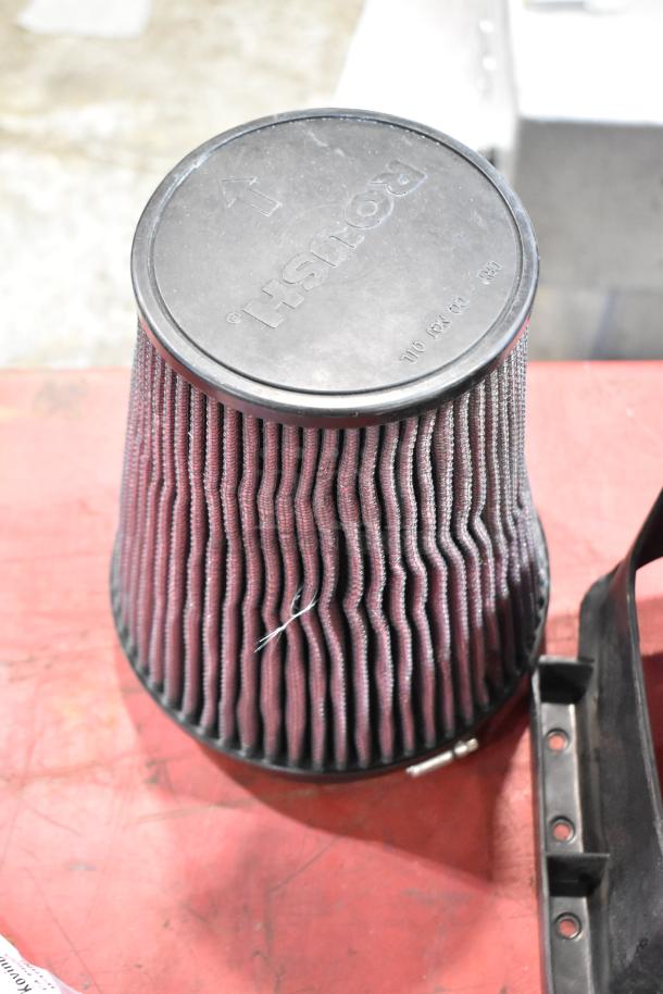 Box of parts featuring a Roush 131550-CAKHK-AB cold air intake filter, used, with visible logo and part markings.