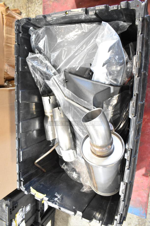 Box of parts in black poly bin, includes metal exhaust components, stored in plastic bags, appears unused.