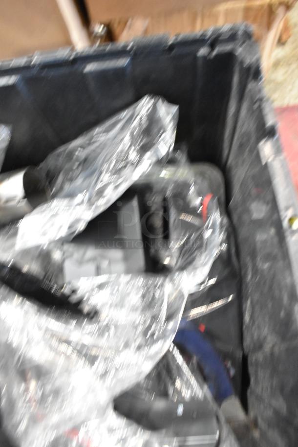 Black poly bin filled with assorted parts, including an exhaust component. Parts are wrapped in plastic; condition varies.