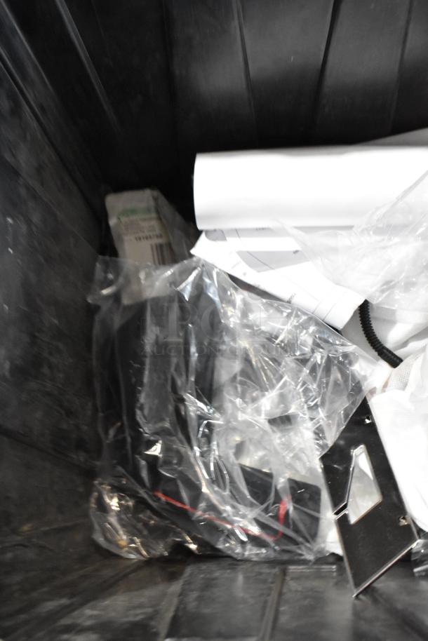 Box of assorted parts, including a headrest, in a black poly bin. Items in clear plastic bags.
