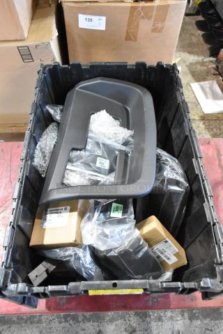 Box of various GMC parts in black poly bin, including panels, new and packaged, with labels indicating part numbers.