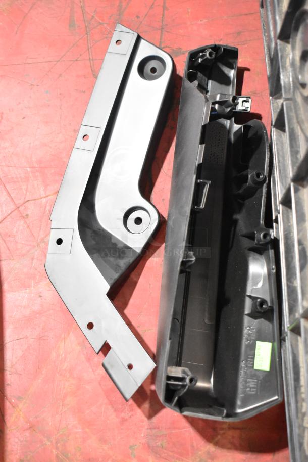 Box of GMC vehicle panels with mounting holes, black poly bin, good condition, visible GM markings.