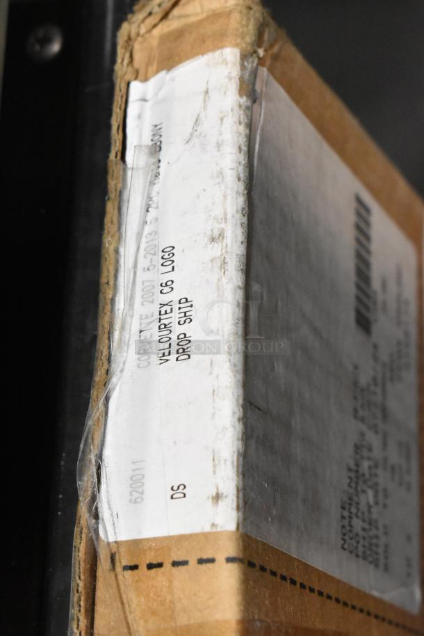 Cardboard box labeled "Corvette 2007-2013 Velourtex C6 Logo Drop Ship," potentially containing floor mats. Marks of wear visible.