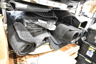 22 various car floor mats, rolled and stacked on shelves. Includes rubber and carpet types, in new condition. Lot label visible.