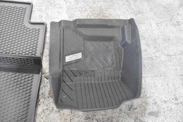 Black car floor mats, two styles shown. One with textured pattern, one with brand logo. New condition. Lot of 24 mats.