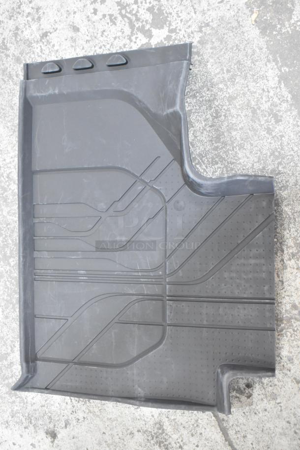 Black rubber car floor mat with textured surface and raised edges, shown on concrete floor. Appears in good condition.