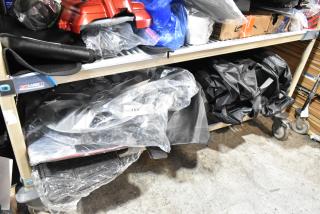 Auction lot featuring various items including a hubcap and panels, stored on shelves. Includes items in bags, label "153."