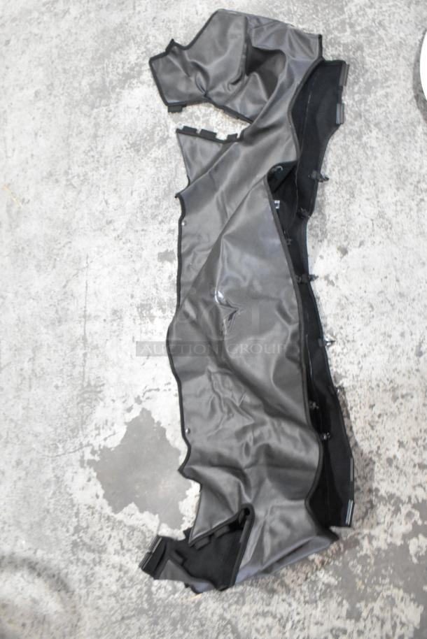 Assorted lot including a wrinkled dark gray automotive panel on concrete floor. Condition: used.