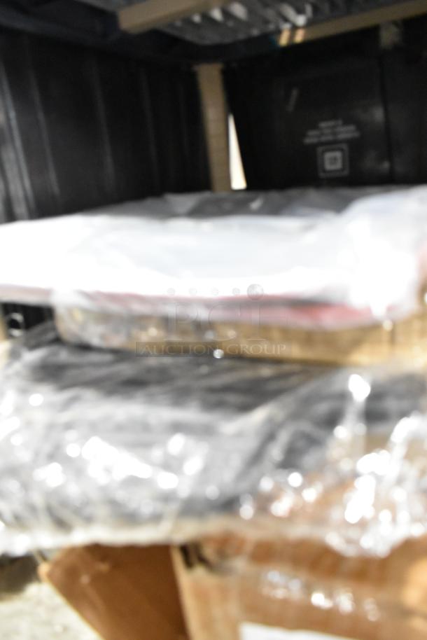 Tier lot of assorted items wrapped in plastic, featuring a hubcap and panels. Items are stacked, with some packaging visible.