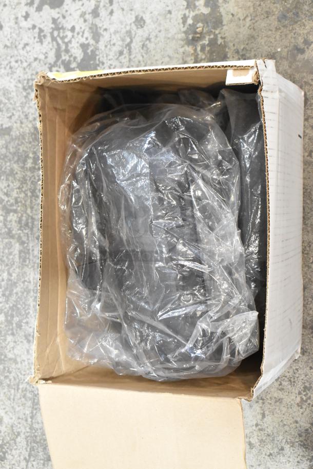 Cardboard box containing assorted items like printer paper and car parts, wrapped in clear plastic, visible from the top.