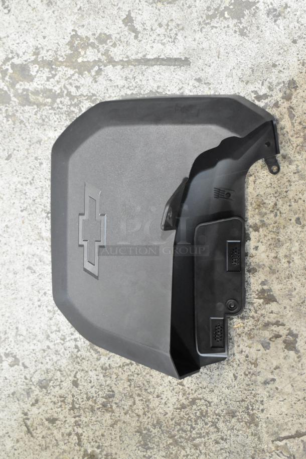 Plastic car engine cover with Chevrolet logo, sleek black finish, appears in good condition, part of auction lot.