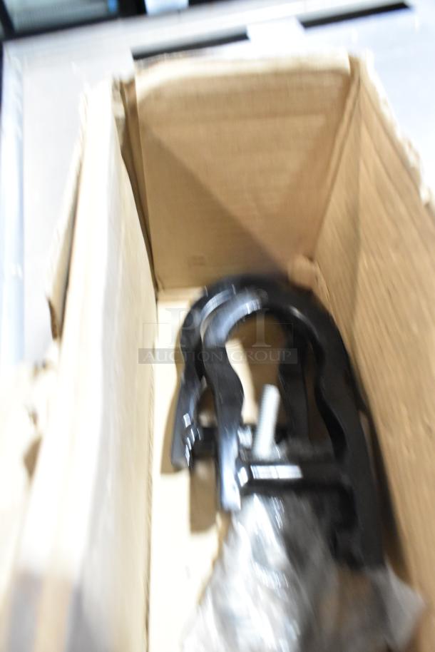 Box containing various items including black car part, possibly unused, on a blurred background.