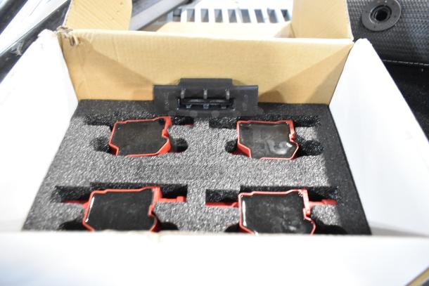 Box containing car parts, including red and black components, in protective foam. Box is slightly worn.