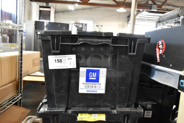 Black poly bin containing various items, including GMC parts. GM label visible, marked for customer care and aftersales, MAC29429.