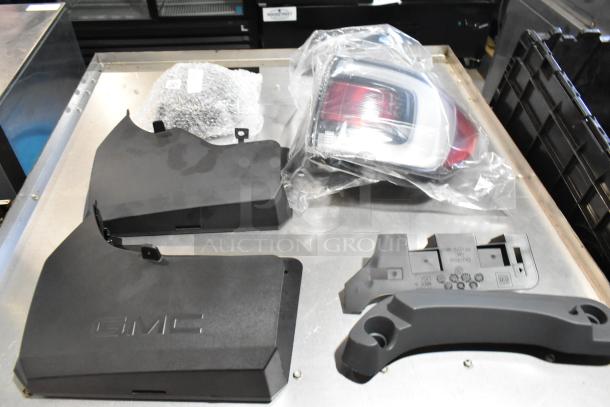 Lot of various items including GMC parts in black poly bin, featuring black panels with GMC logo and a wrapped tail light.