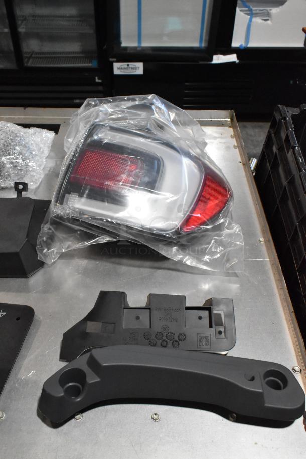 Lot of various GMC parts in a black poly bin, including a wrapped tail light and plastic components with GM markings.